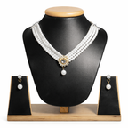Luxurious design: Four strands of lustrous white pearls converge at a gold-toned floral centerpiece adorned with sparkling crystals and a dangling pearl drop.